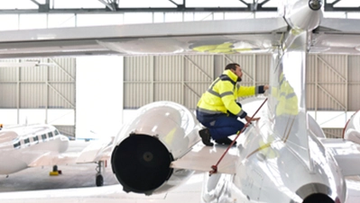 Techniker in Warnschutzjacke bei der Wartung eines Flugzeugs in einem modernen Hangar – RMS Ground Support Equipment im Einsatz